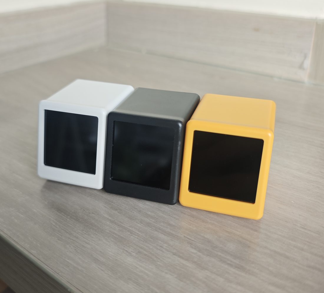 BGMate mini in white, graphite and amber, side by side on a wooden table
